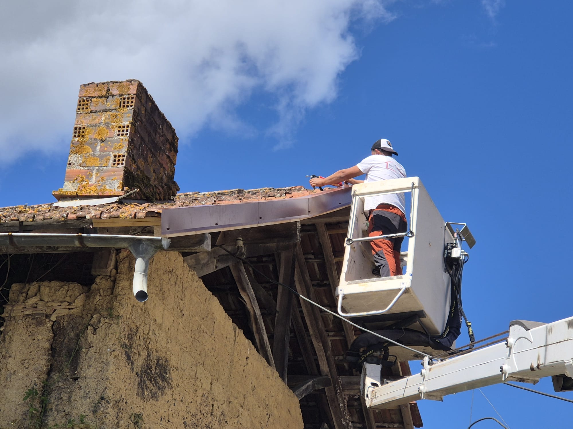 Artisan couvreur intervenant en nacelle sur une toiture