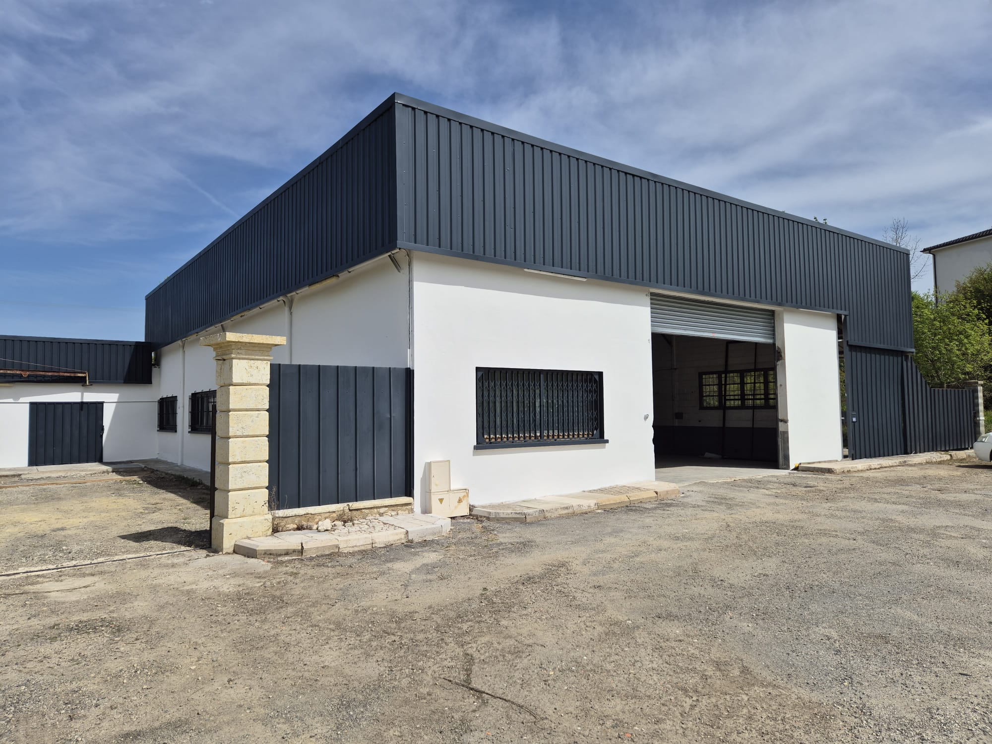 Bâtiment professionnel rénové avec bardage anthracite et façade blanche